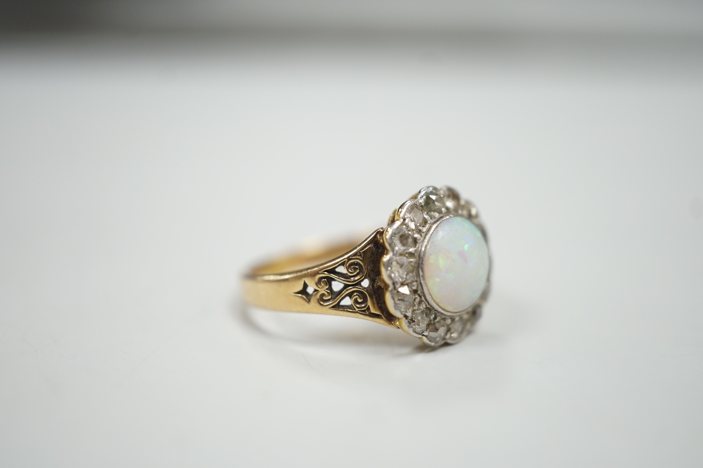 A 1920's? yellow metal, white opal and round cut diamond set circular cluster ring, size O, gross weight 3.6 grams.